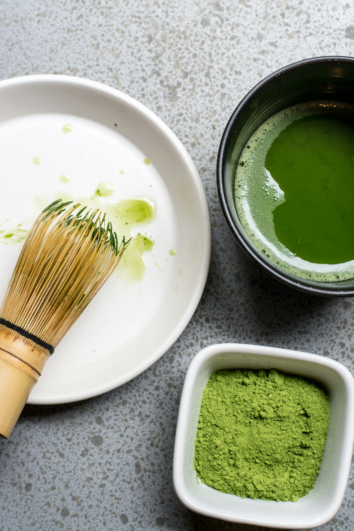 白い皿と黒い茶碗に入った抹茶(緑茶粉末)、竹製の茶筅